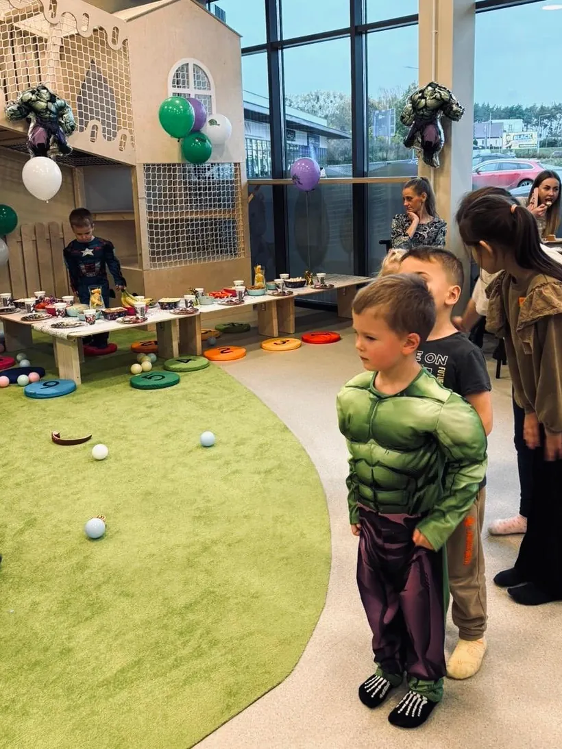 Sala urodzinowa z balonami i dziećmi w strojach superbohaterów
