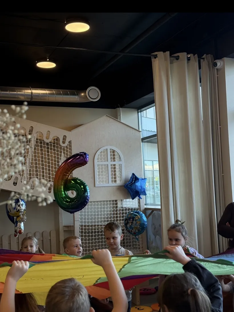 Urodziny w bawialni - balon z cyfrą 6 i dzieci przy stole