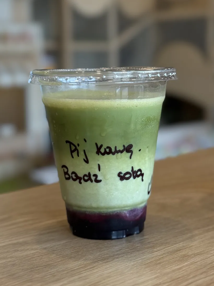 Matcha w kubku z odręcznym napisem na drewnianym blacie