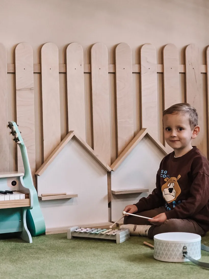Chłopiec gra na drewnianych instrumentach w kąciku muzycznym